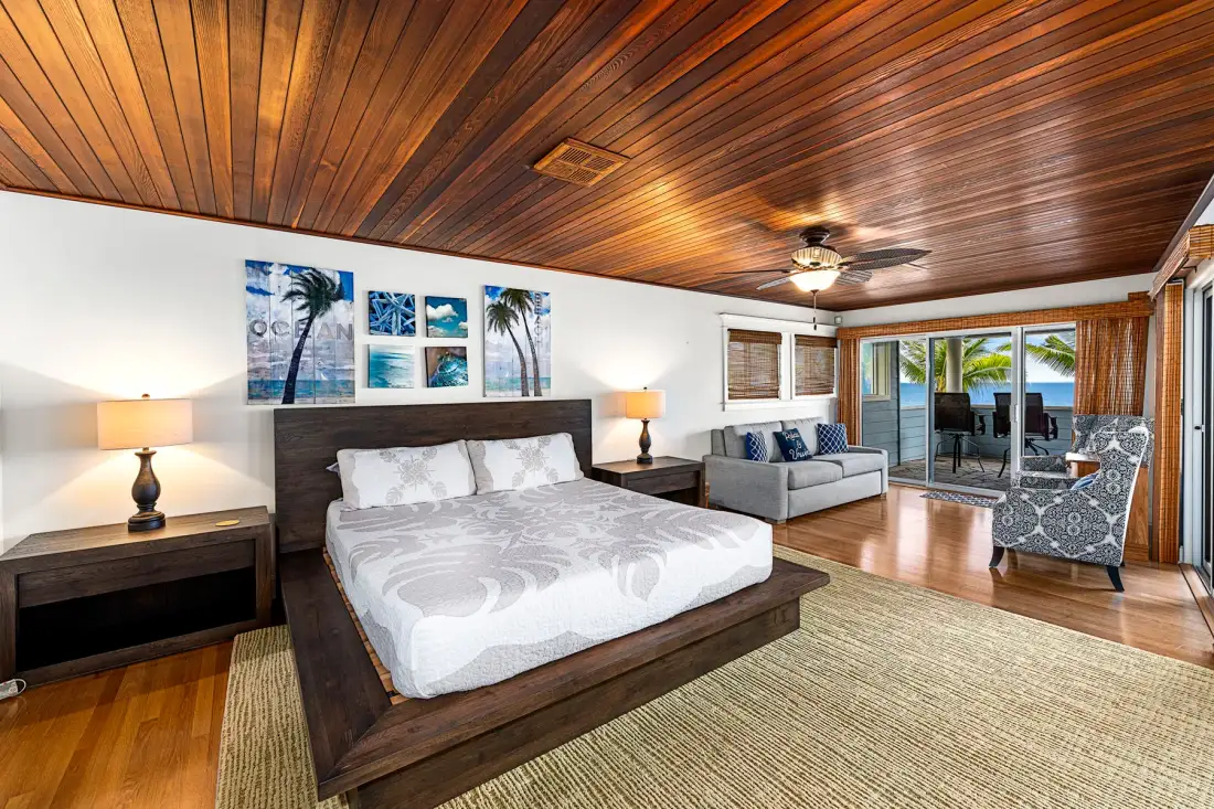Un dormitorio con una cama grande, una zona de estar y puertas corredizas de vidrio.