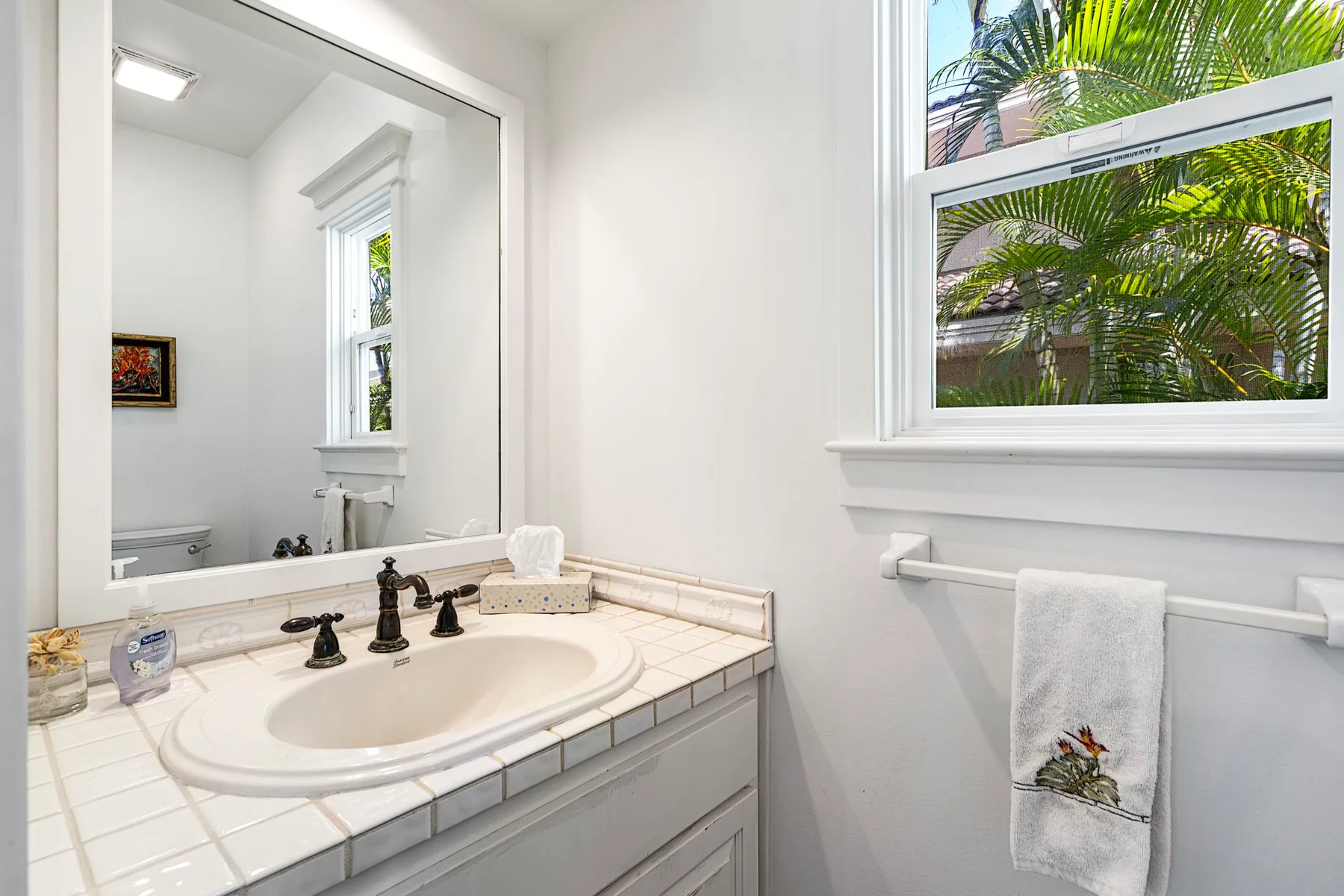 Un tocador de baño luminoso con lavabo, espejo y ventana.