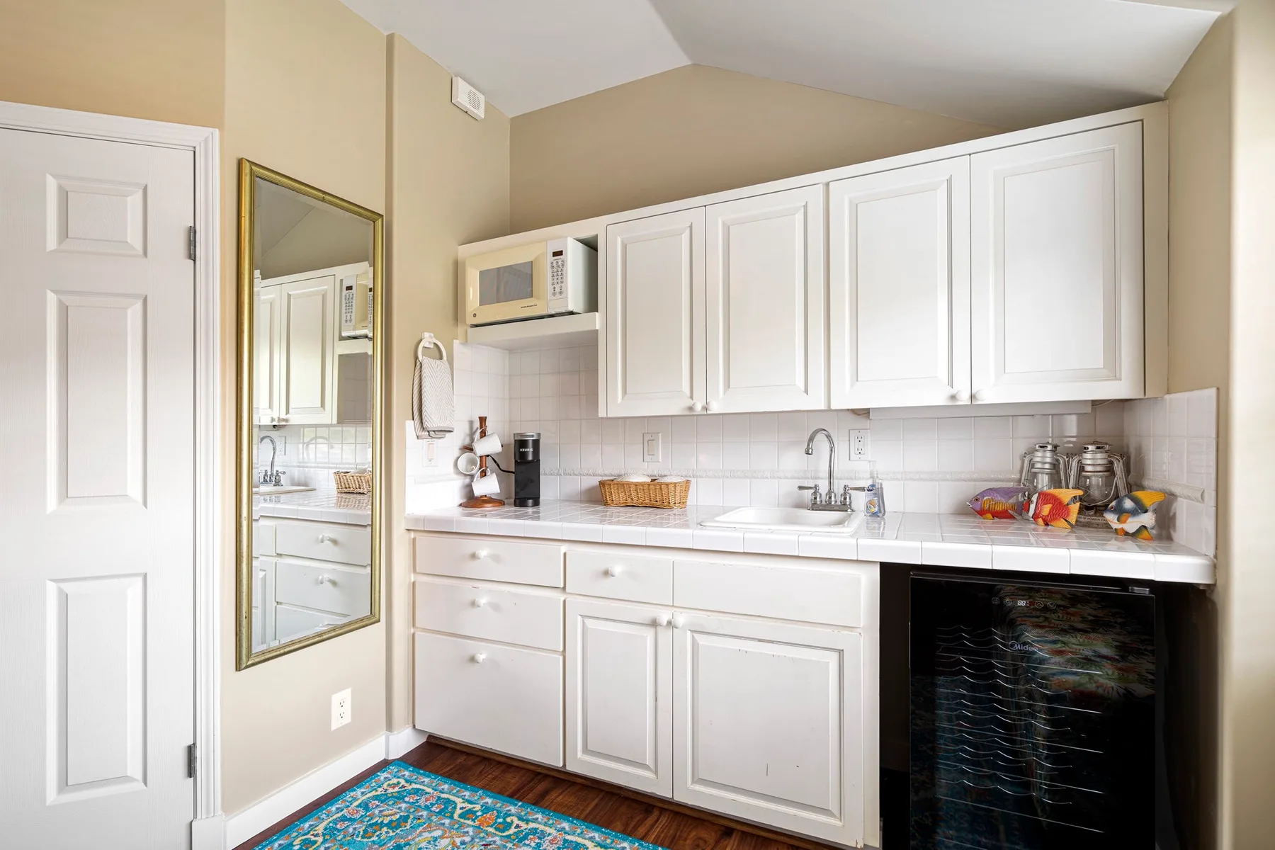 Una cocina compacta con gabinetes blancos, una encimera y un mini refrigerador negro.