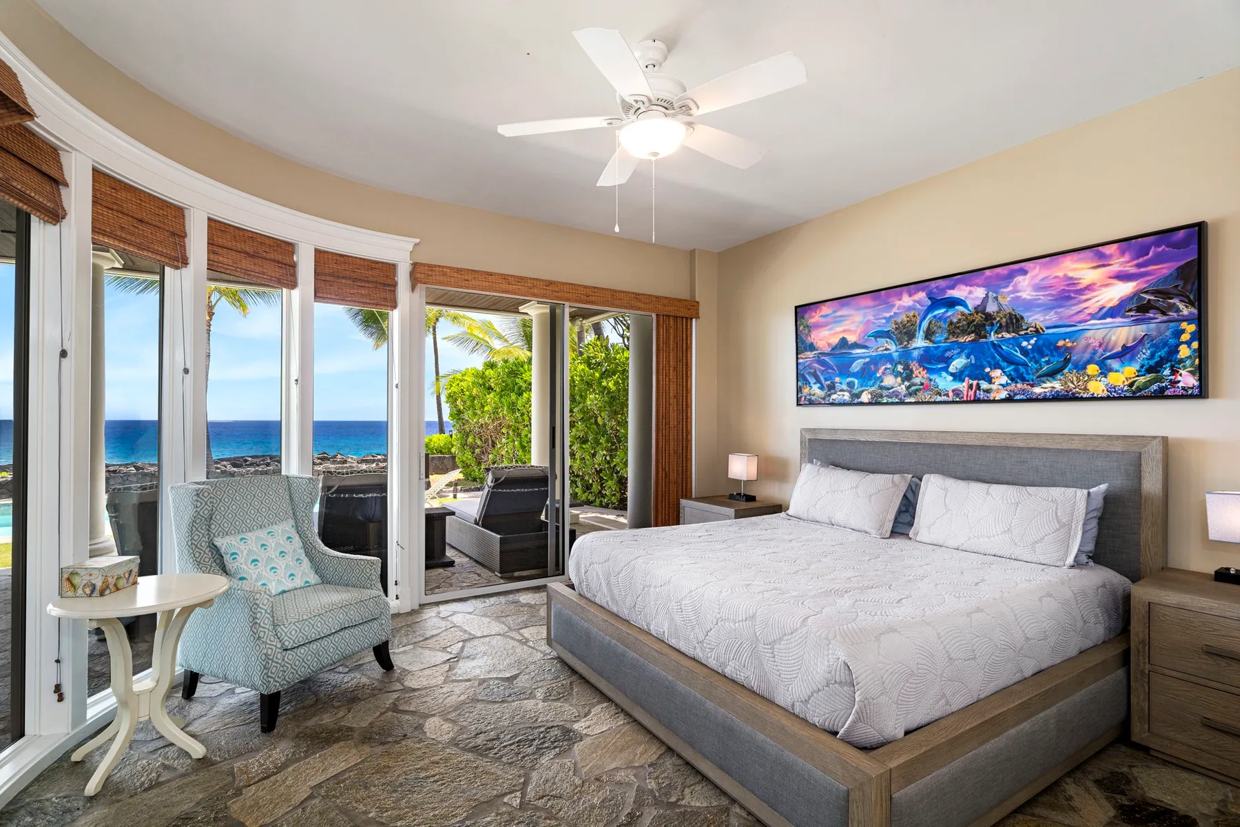 Un dormitorio con una cama grande y asientos junto a ventanas con vista al mar.