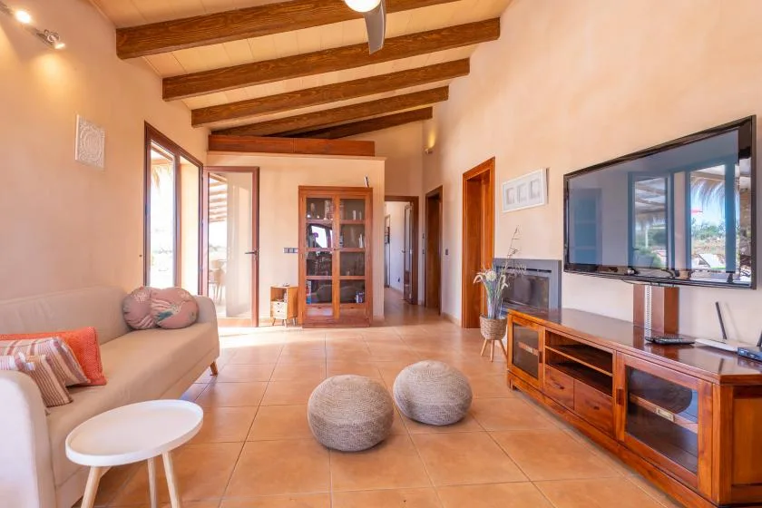 A bright living room with seating, a television, and exposed ceiling beams.