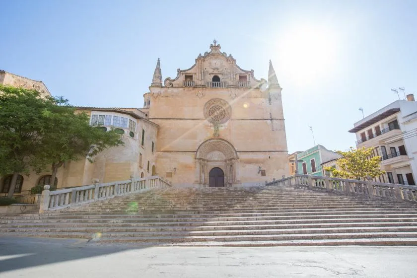 A stone church stands above broad steps in a sunny town square.