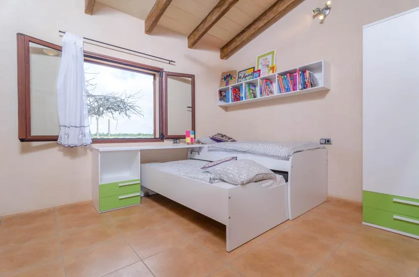 A bedroom with a bed, a desk, and a wall-mounted bookshelf.