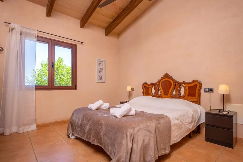 A bedroom with a bed dressed in light bedding and a window with curtains.