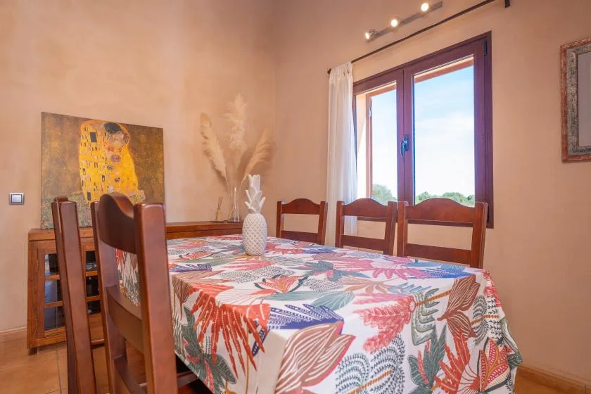 A dining room with a patterned tablecloth and a large window.