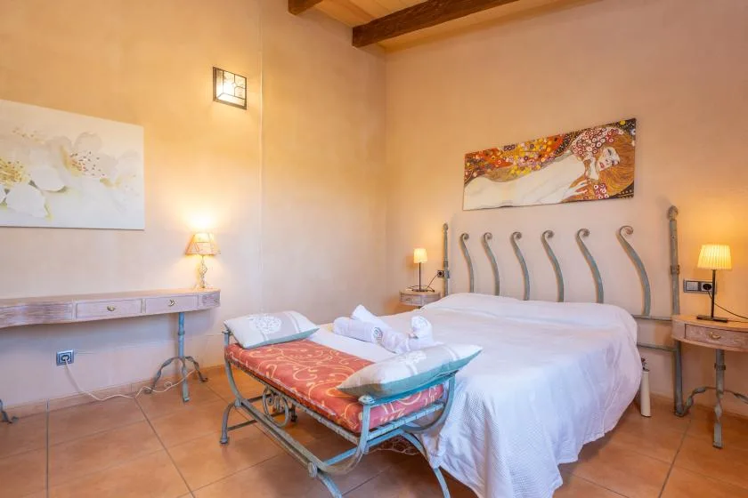 A bedroom with a large bed and a cushioned bench at its foot.