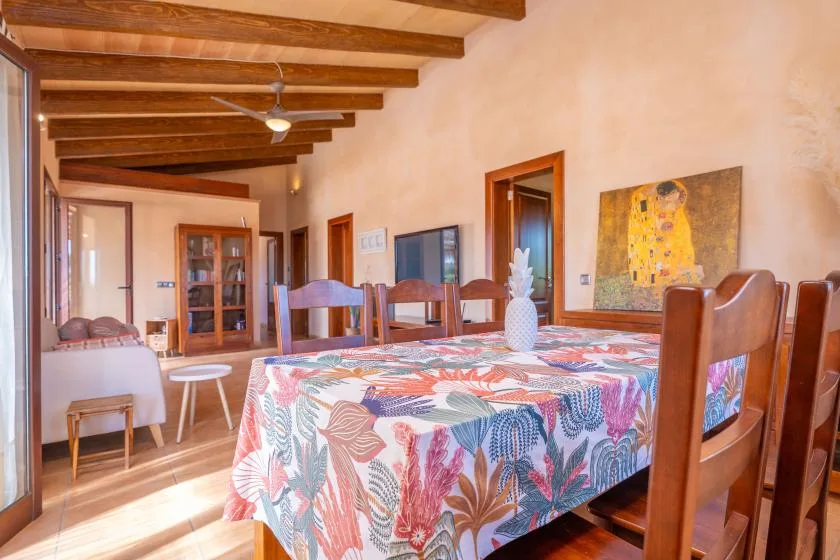 A dining room with a floral tablecloth and wooden dining furniture.
