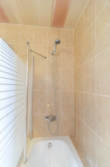 A tiled bathroom with a bathtub and wall-mounted shower.