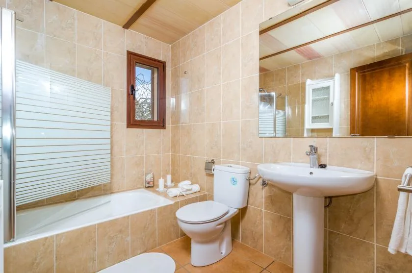 A tiled bathroom with a bathtub, toilet, and pedestal sink.