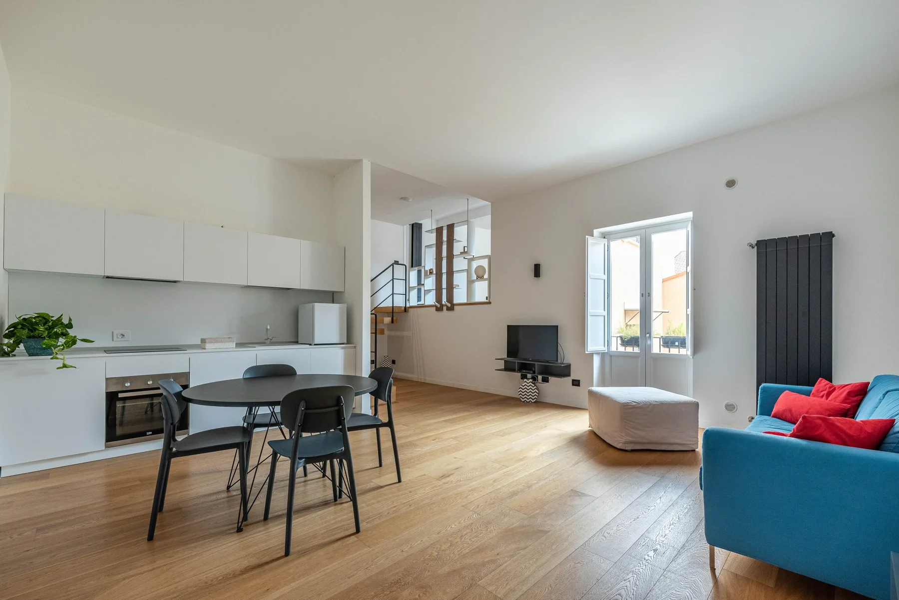 An open-plan living and dining area includes a kitchen and blue seating.