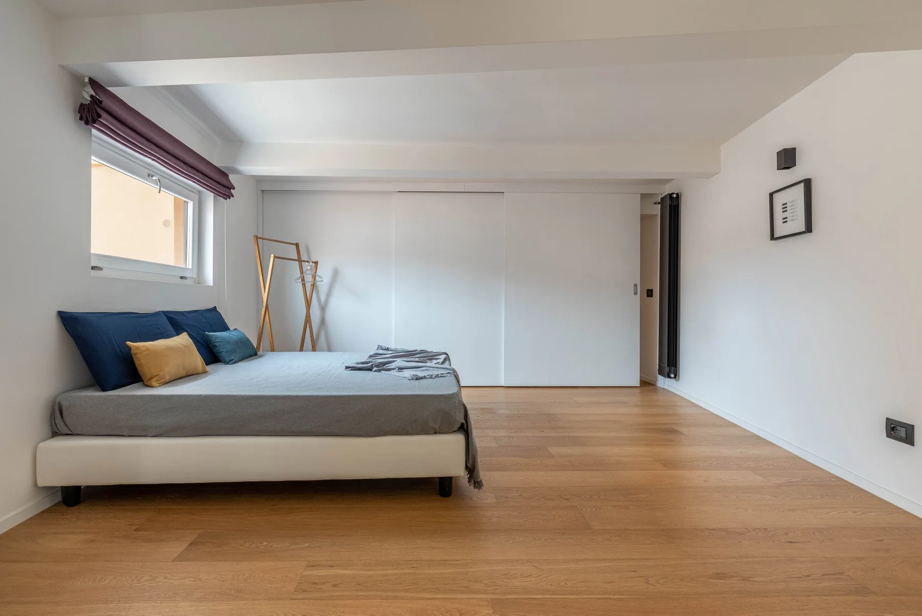 A bedroom with a low bed, wooden floor, and a large sliding closet.