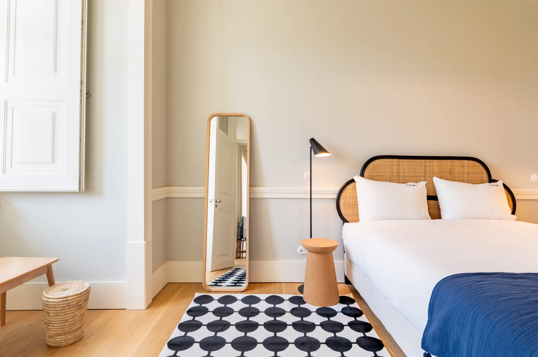 Dormitorio con cama, mesa auxiliar y alfombra estampada.