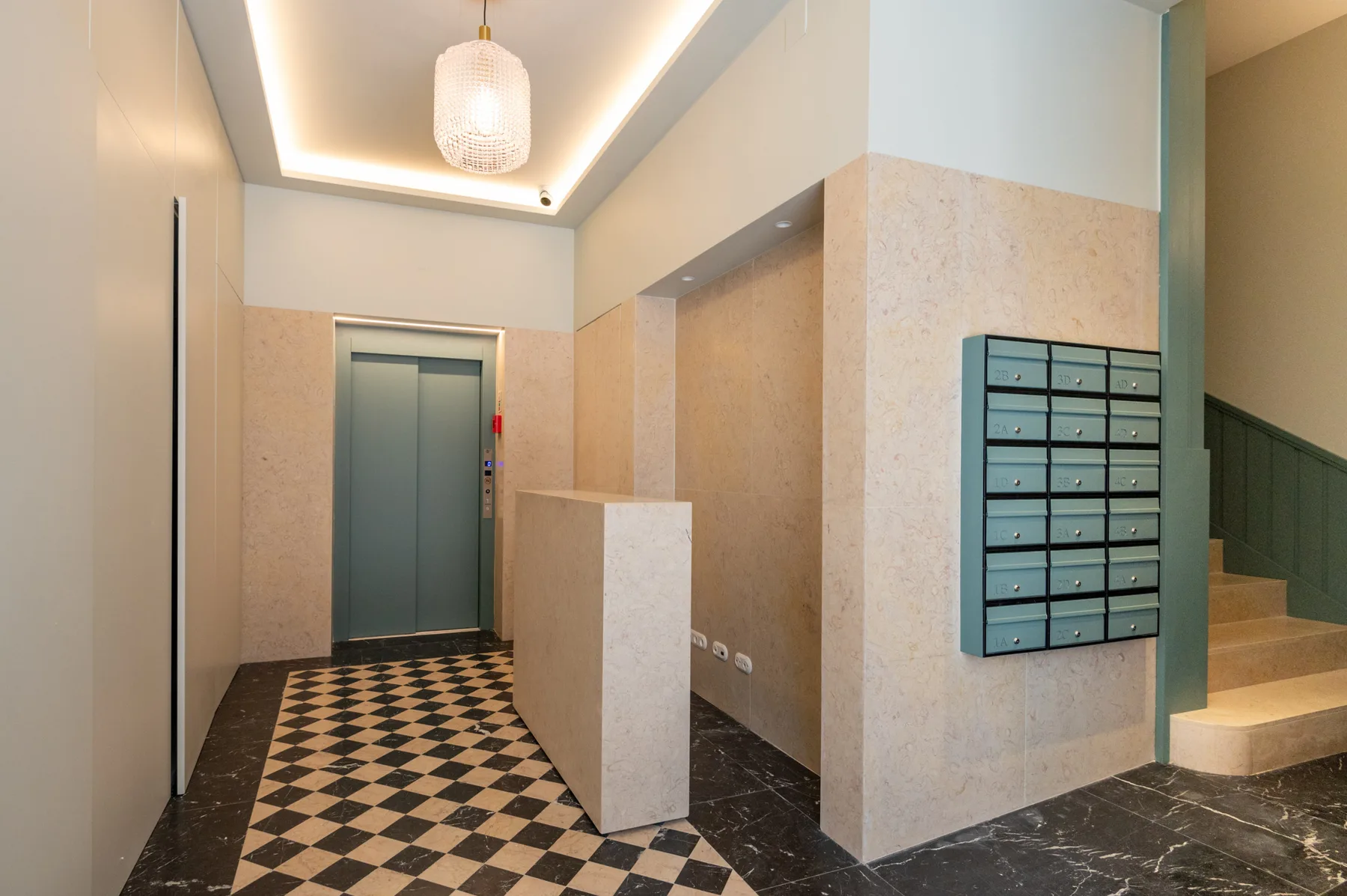 An apartment building lobby with a patterned tile floor, elevator, and wall-mounted mailboxes.
