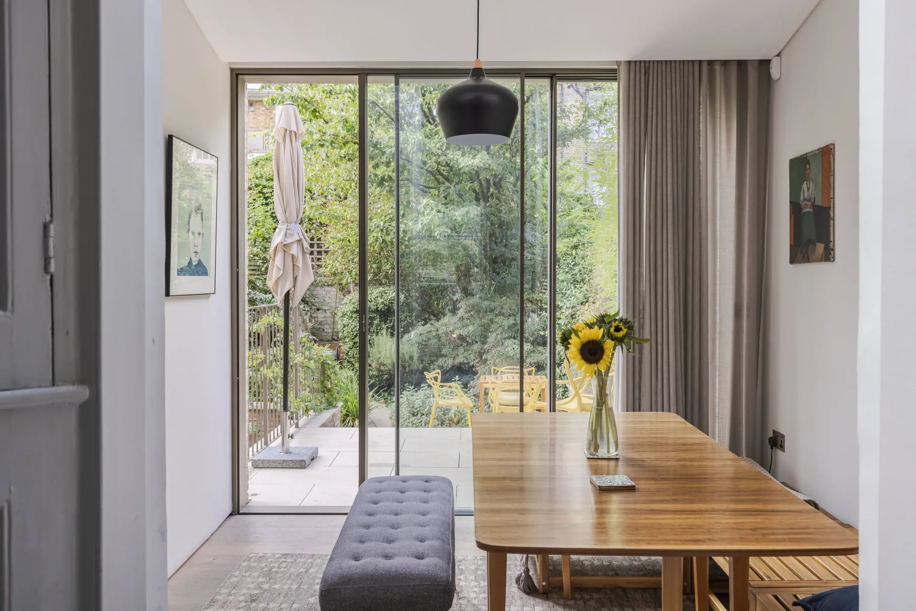 Comedor con una mesa de madera junto a grandes puertas de vidrio que dan a la vegetación.