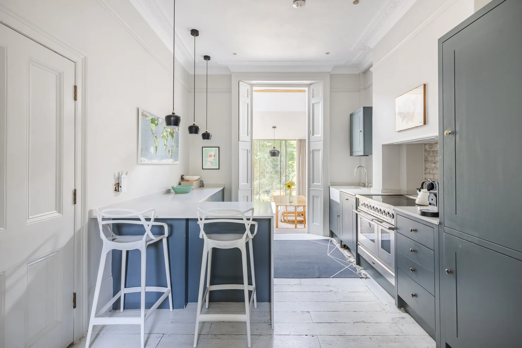 A bright kitchen with a blue island, bar seating, and gray cabinetry.