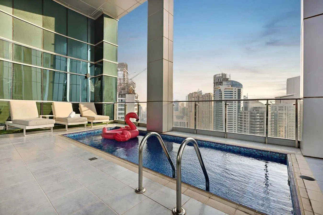Una piscina en la azotea con asientos y el perfil urbano al fondo.