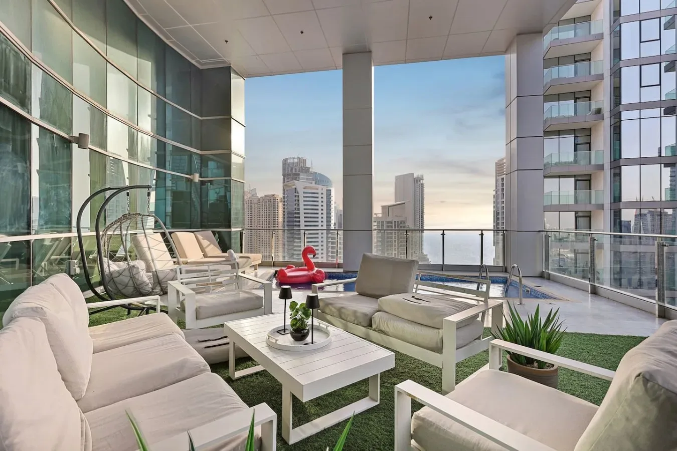 An outdoor seating area with lounge chairs and a glass railing overlooks nearby buildings.