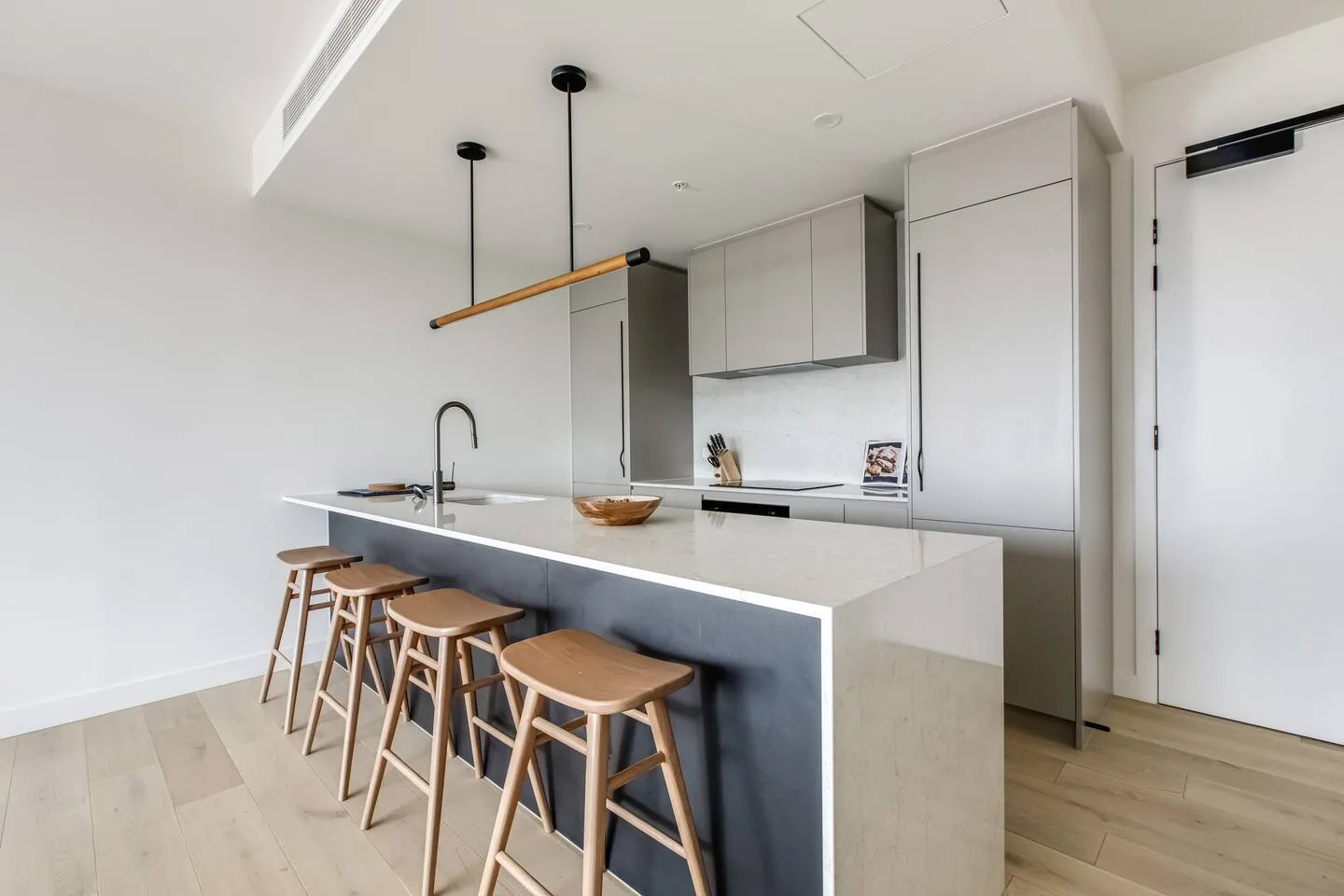 Una cocina moderna y luminosa tiene una isla larga con taburetes de madera.