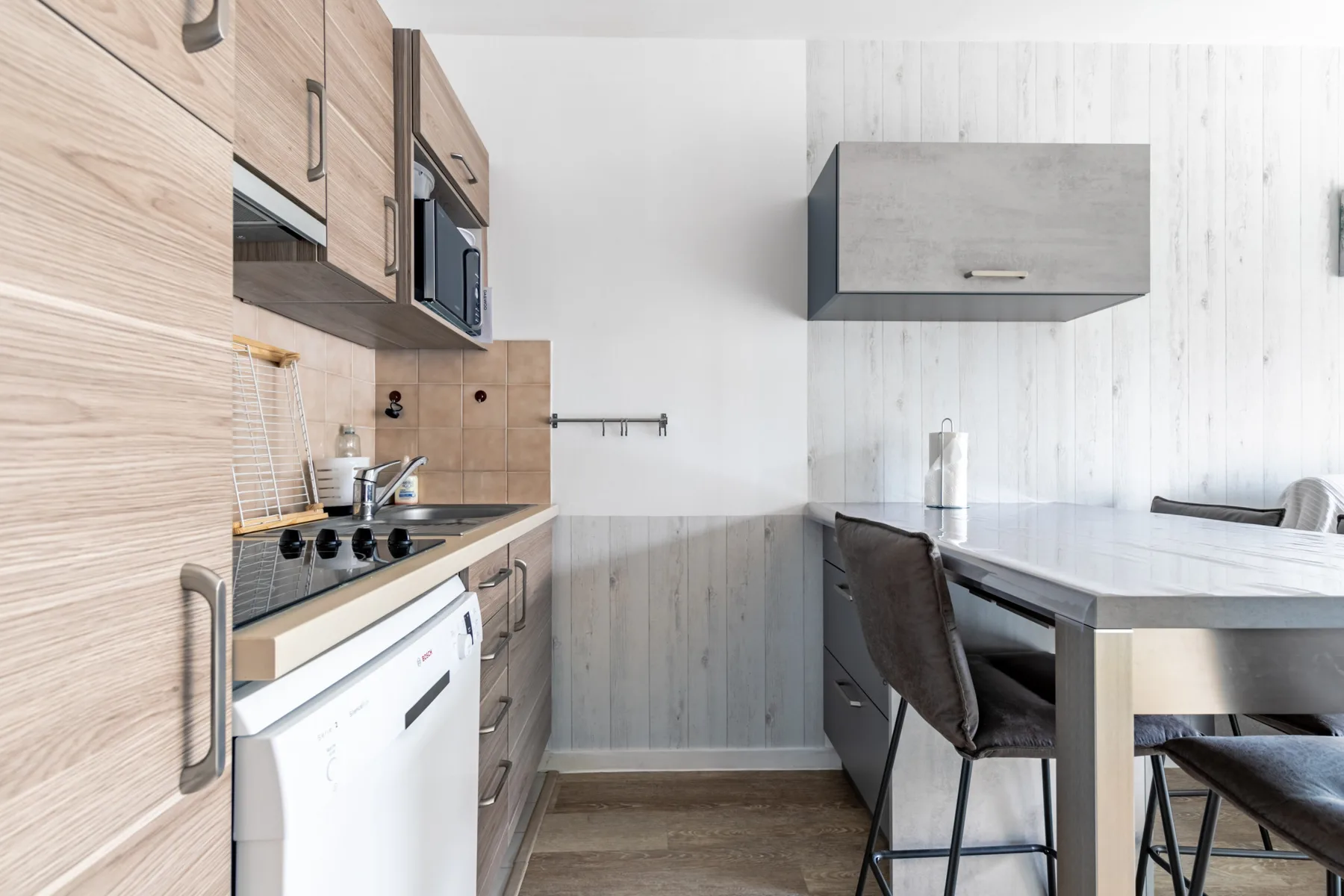 A compact kitchen and dining area with light wood cabinetry and a table.