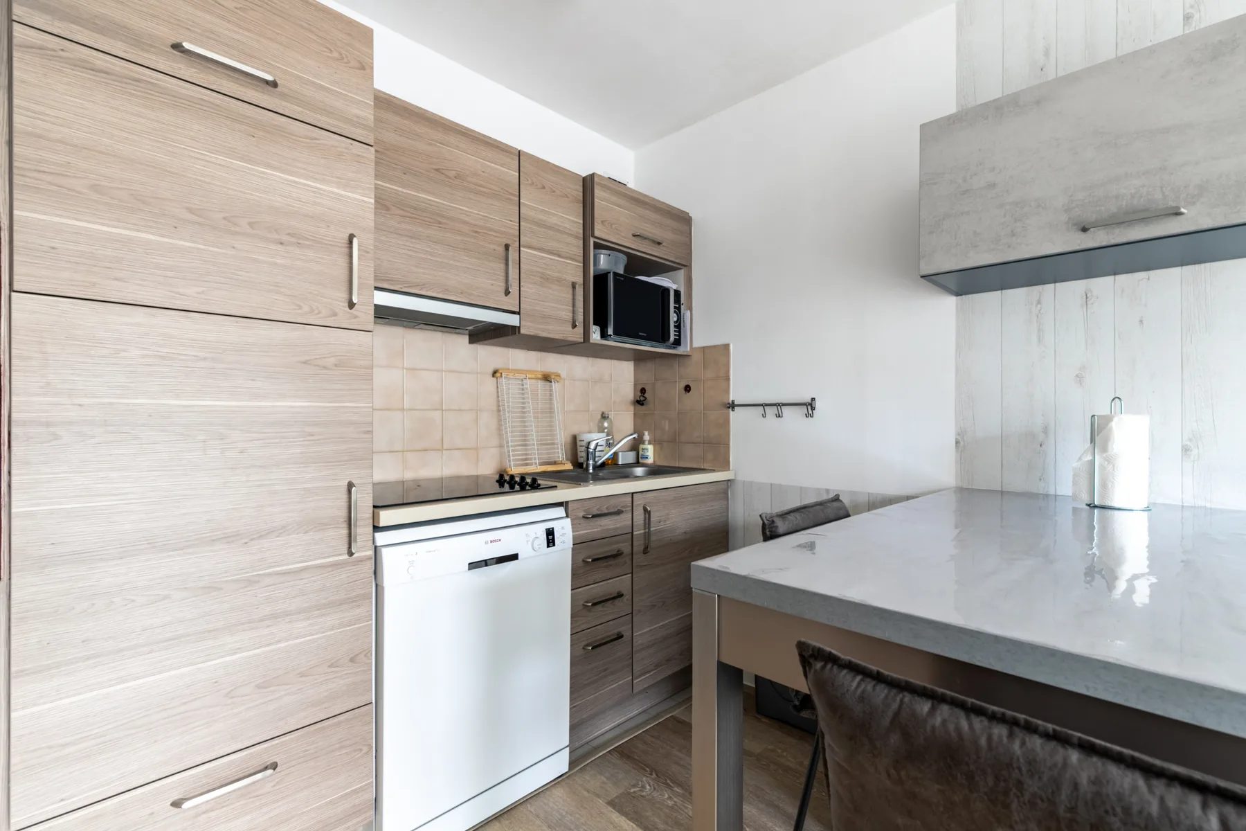 A modern kitchen with wood cabinetry, a sink, and a dining table.