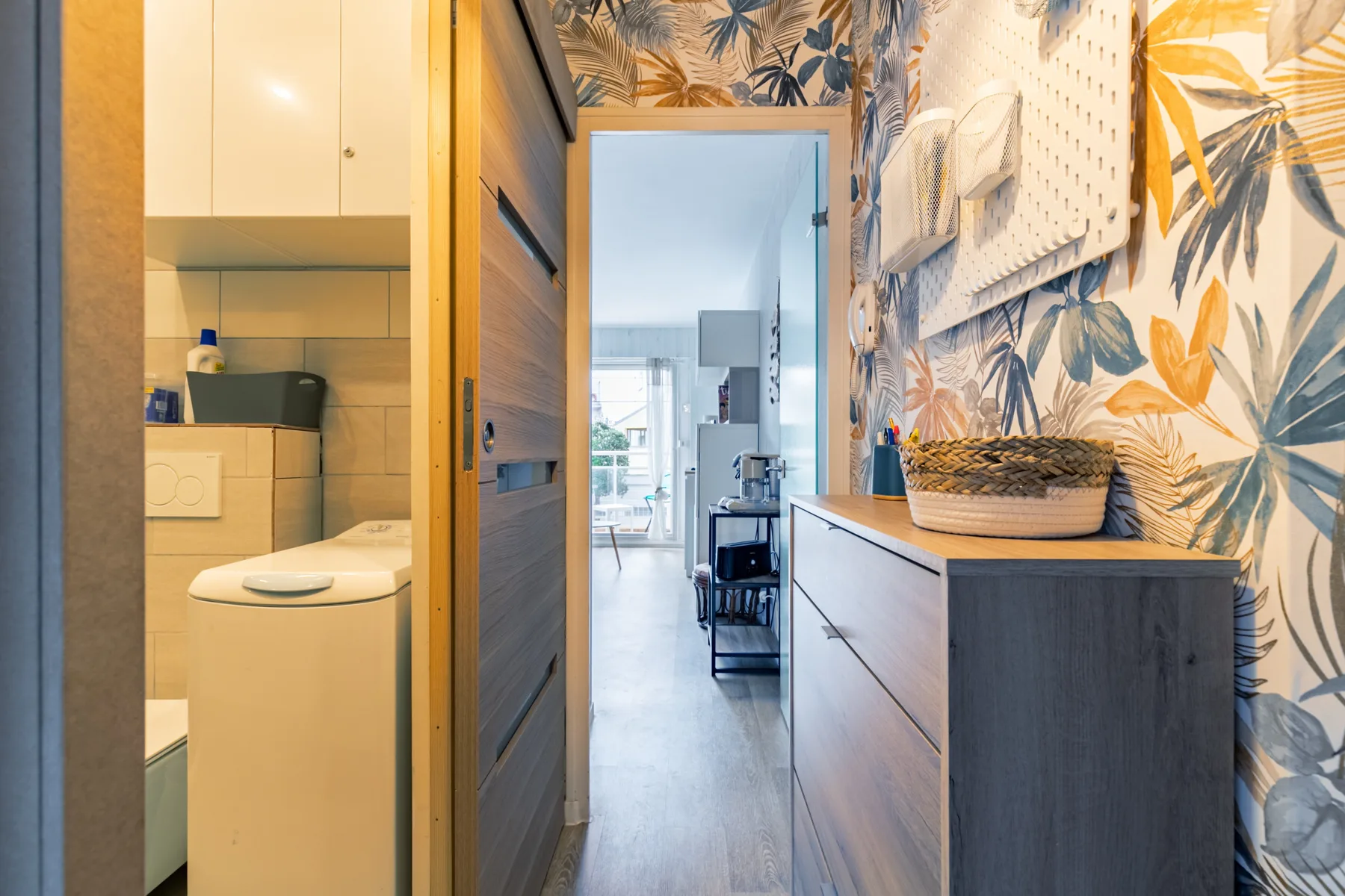 An apartment hallway with a bathroom and patterned wallpaper.