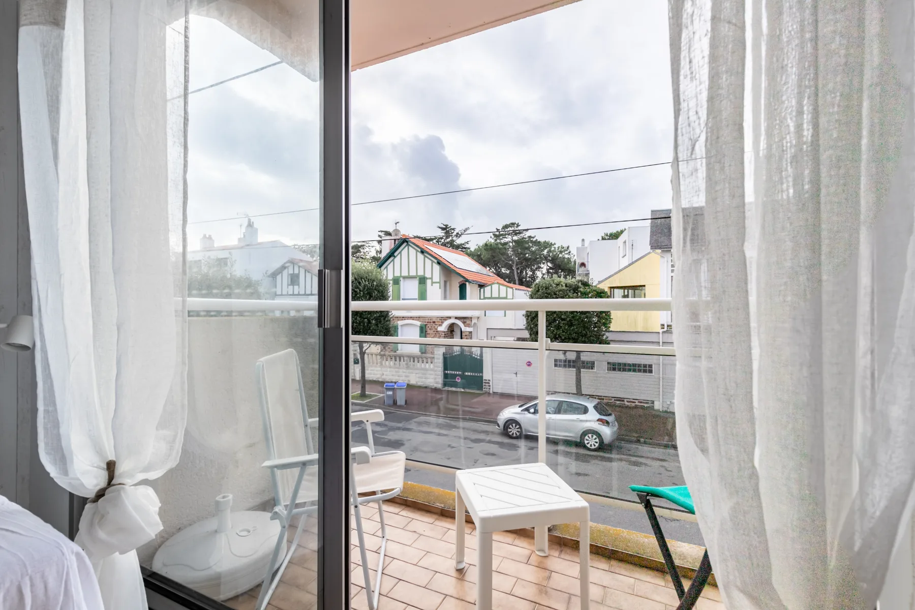A balcony seating area overlooks a street through open glass doors.