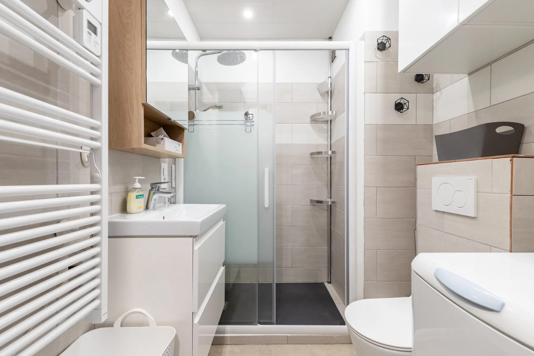 A tiled bathroom with a glass shower and a sink.