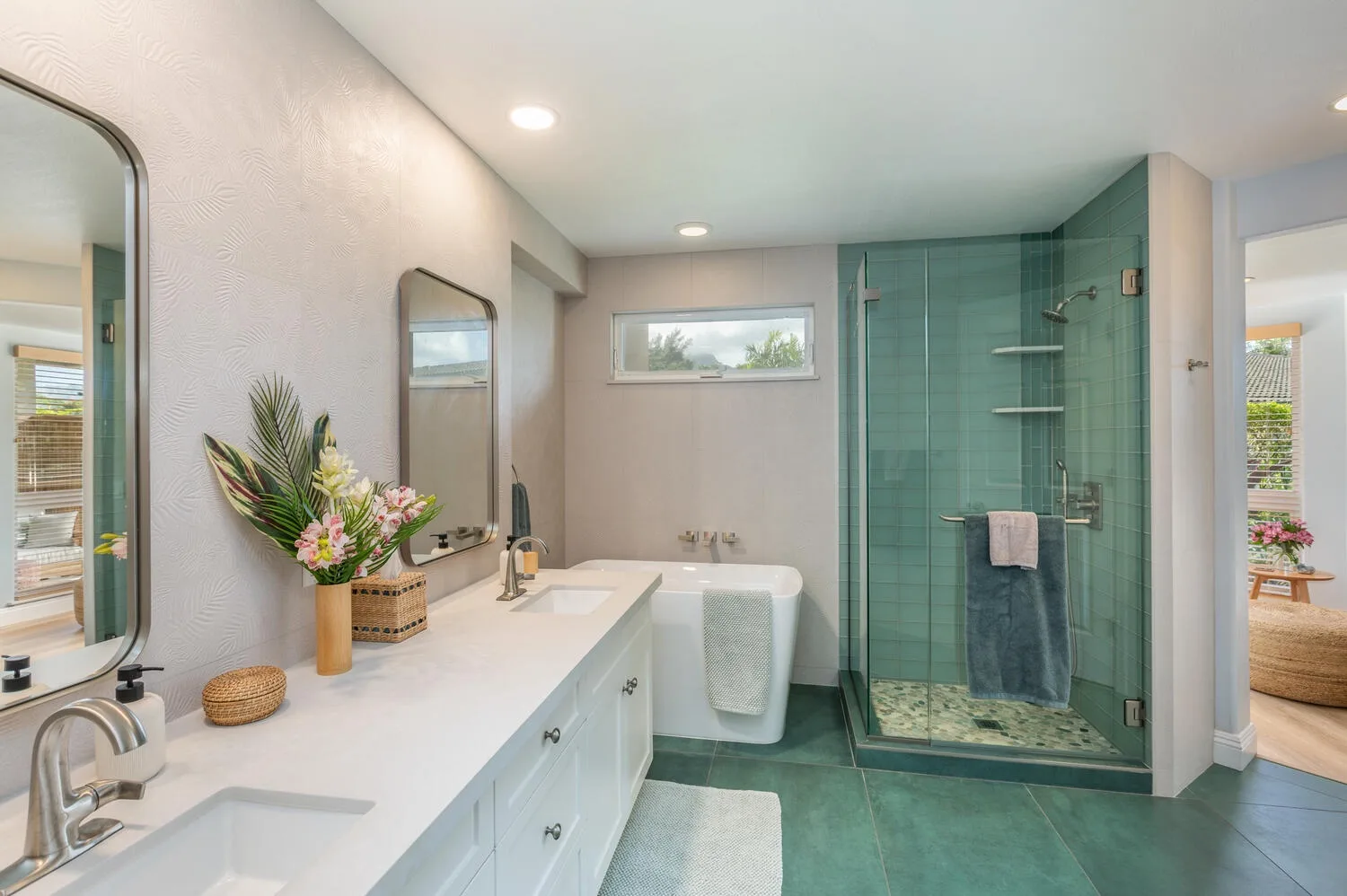 A bright bathroom with a long vanity, bathtub, and glass shower.
