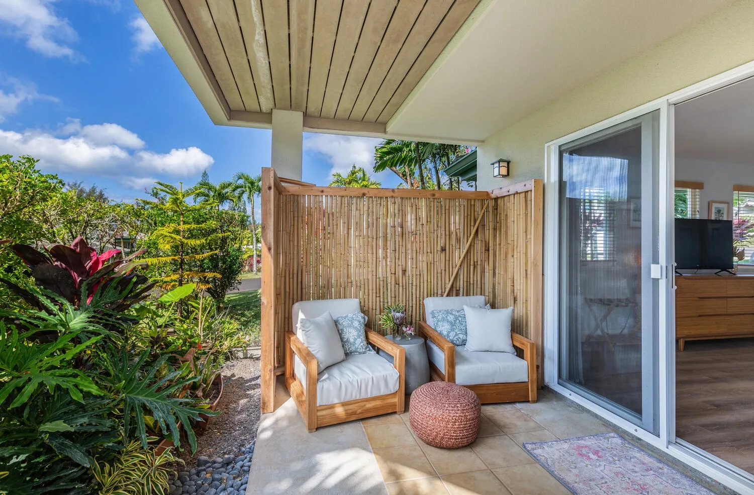 A small outdoor seating area with cushioned chairs beside a sliding glass door.