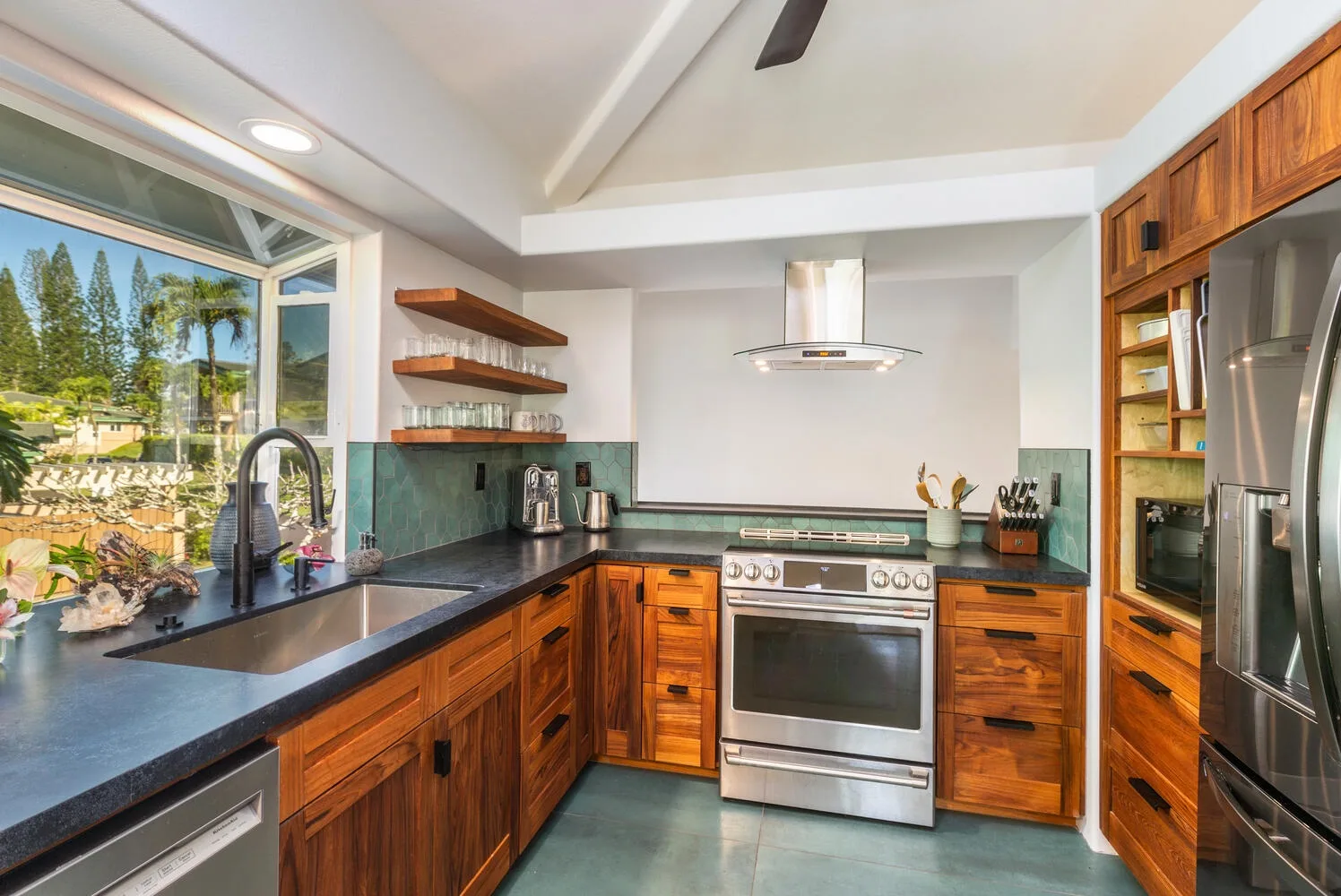 A kitchen with wooden cabinetry, dark countertops, and a stainless steel range.