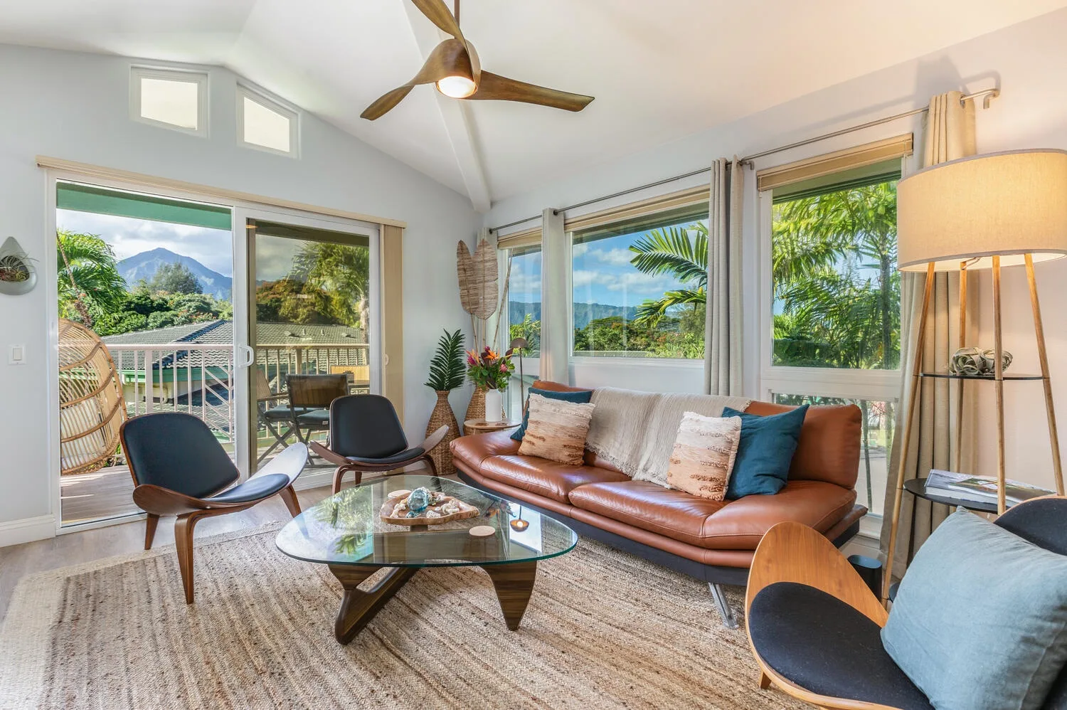 A bright living room with seating around a glass coffee table and large windows.