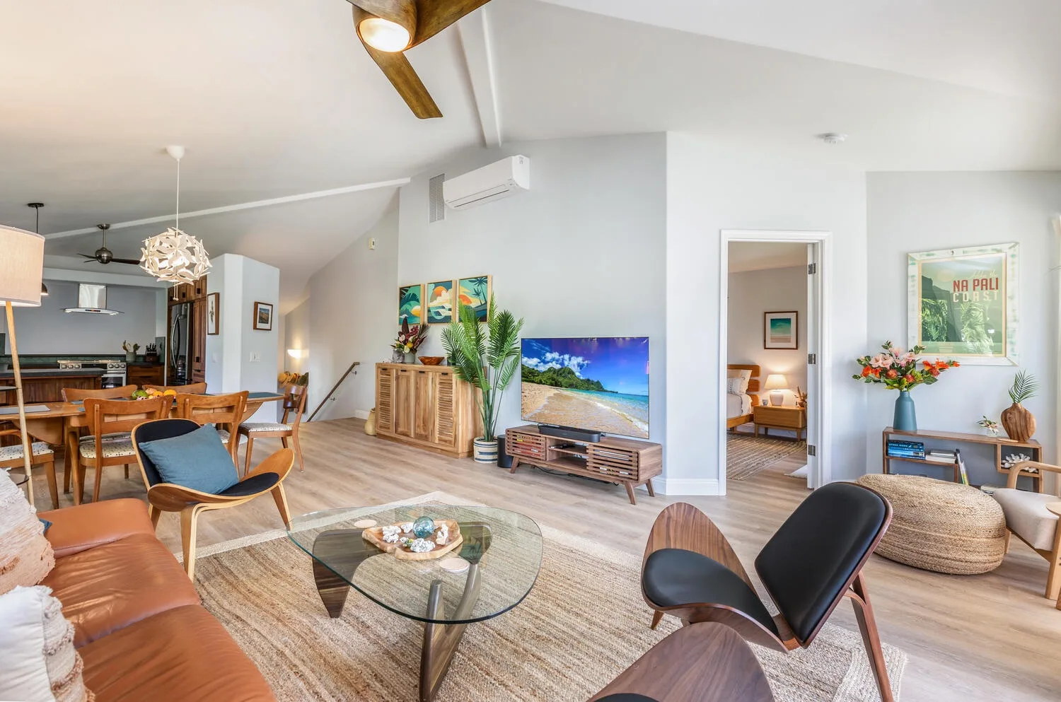 A bright open-plan living and dining area has a glass coffee table and colorful seating.