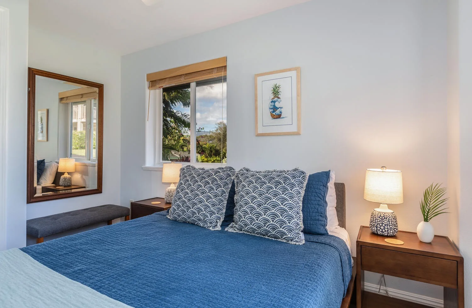 A bedroom with a blue bed, patterned pillows, and bedside tables.