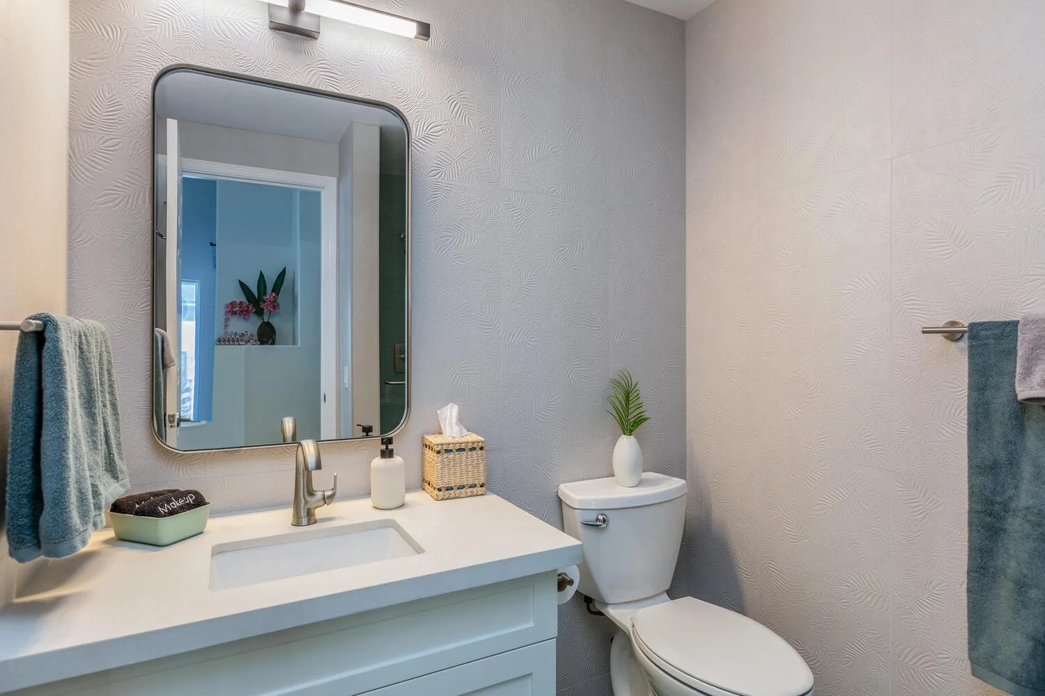 A bathroom vanity and toilet sit beneath a wall mirror.