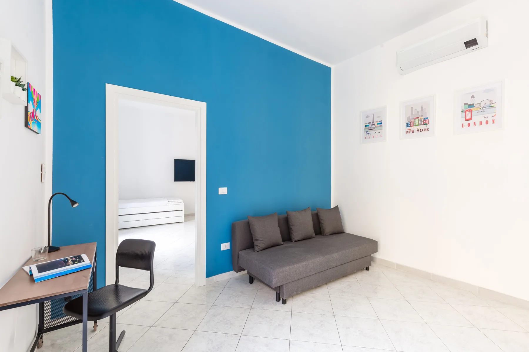A bright living area with a gray seating sofa against a blue accent wall.