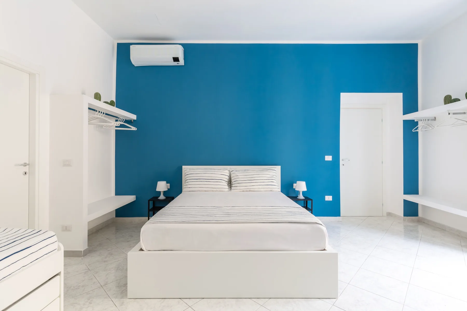 A bedroom with a bed centered against a bright blue wall.