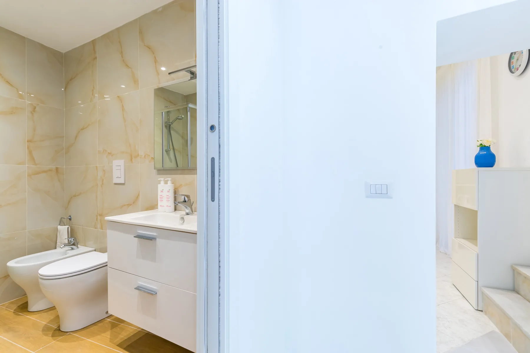 A tiled bathroom with a toilet, sink, and mirrored cabinet.