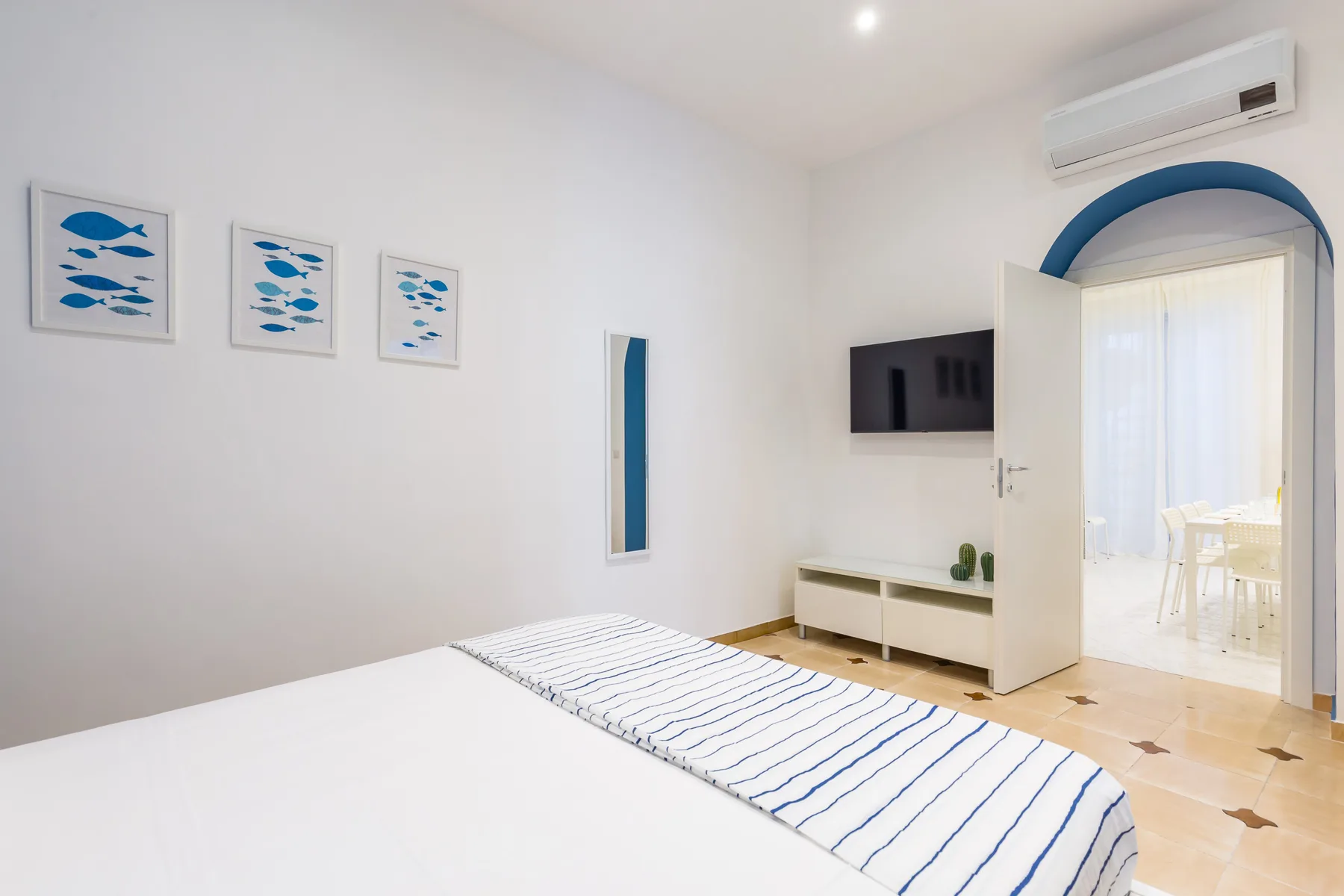 A bright bedroom with a neatly made bed and an open doorway.