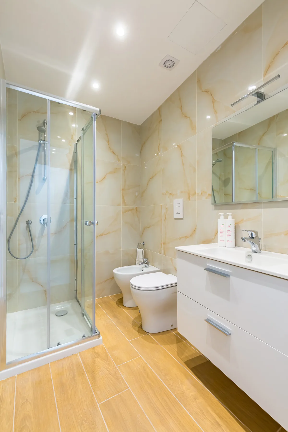 A modern bathroom with a glass shower, toilet, and white vanity.