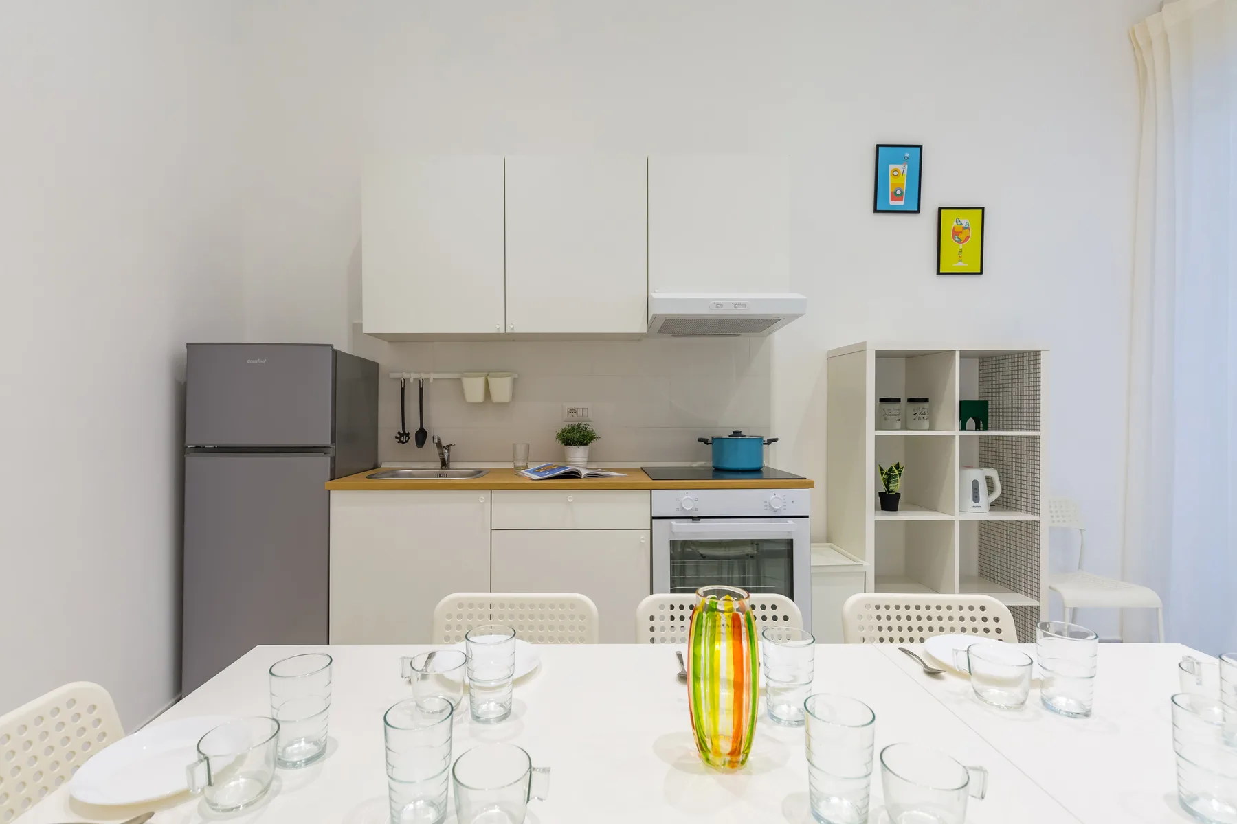 A bright kitchen and dining area with a table set with glassware.