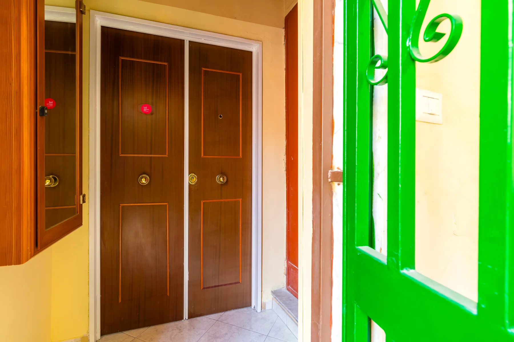 An entryway with dark wooden doors and a bright green metal gate.