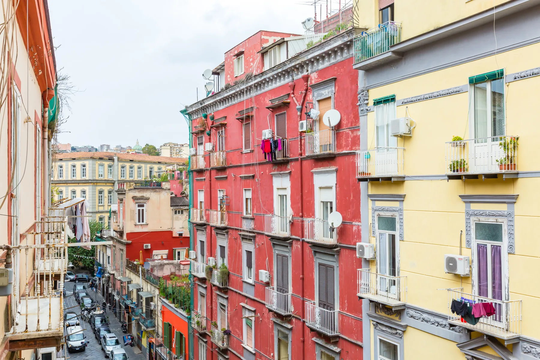 A narrow urban street lined with colorful apartment buildings and balconies.