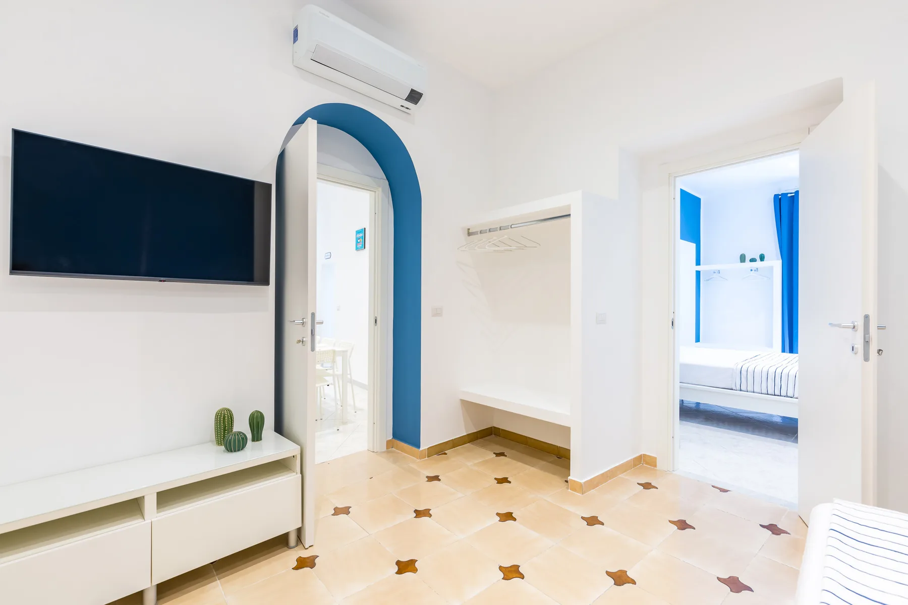 A bright interior hallway with an arched doorway and a wall-mounted television.