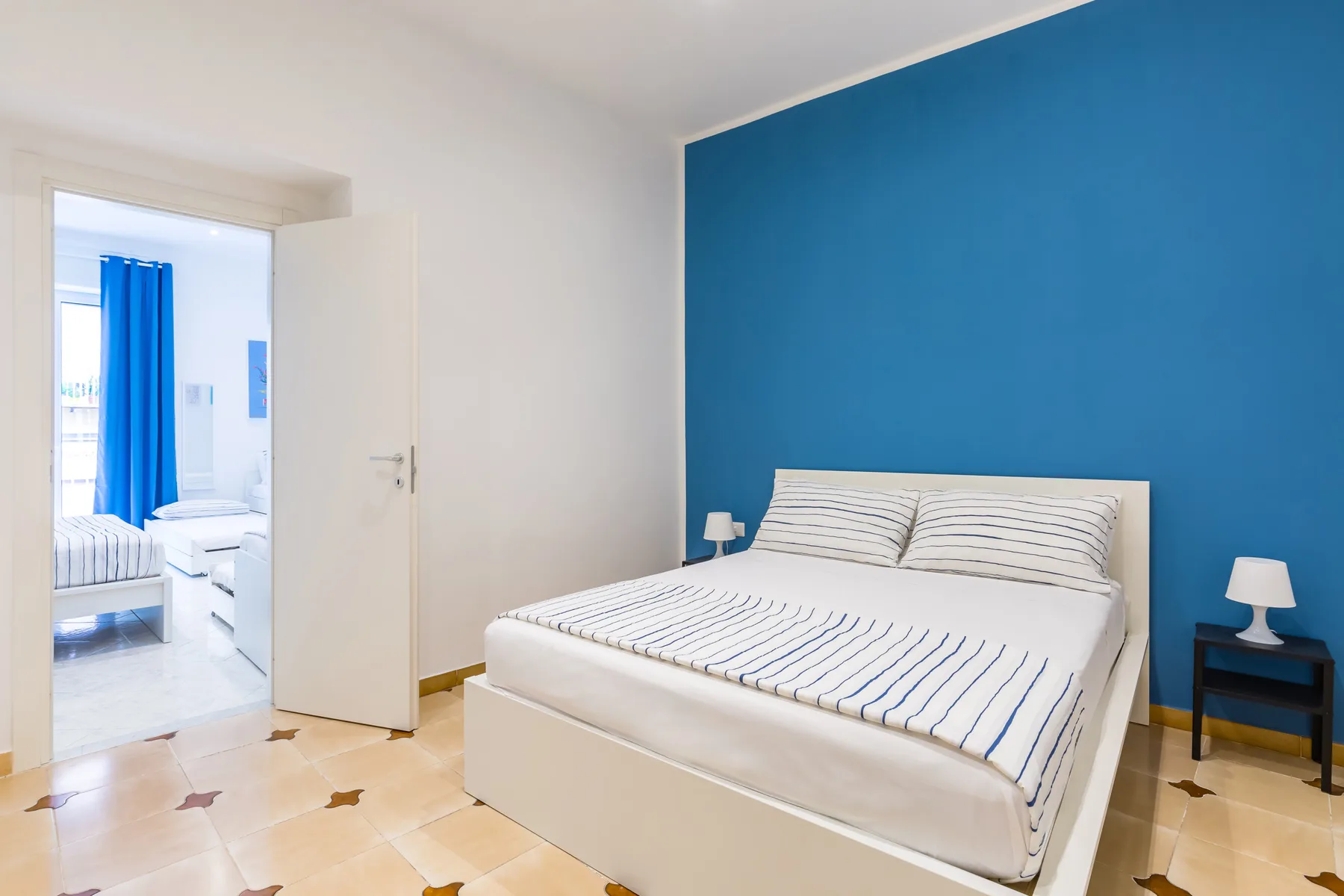 A bedroom with a bed against a bright blue wall.