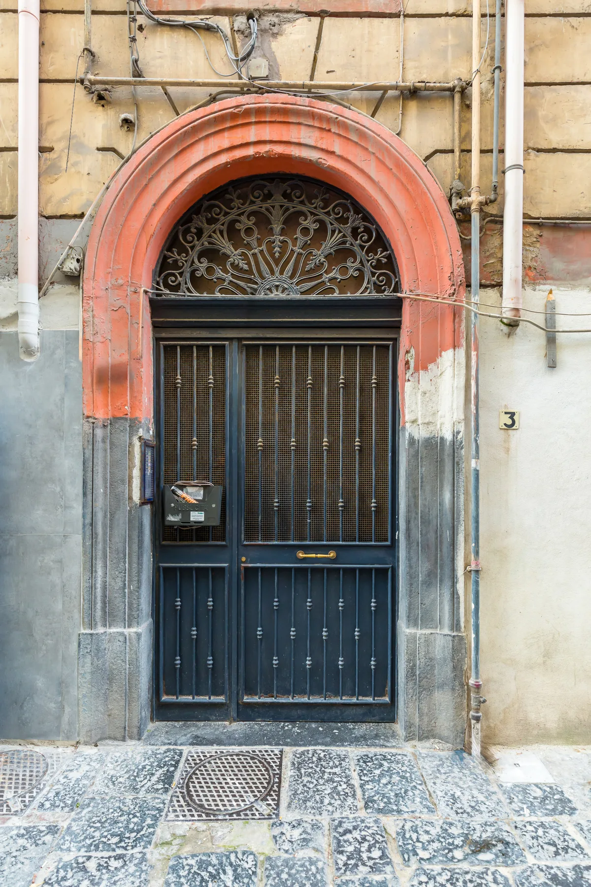 A street-facing building entrance has a dark metal gate beneath a rounded arch.