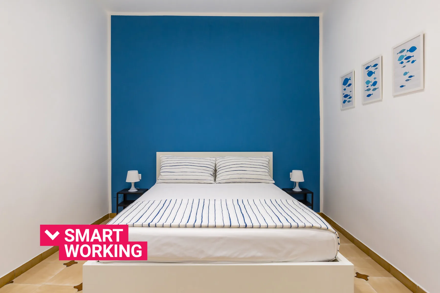 A bedroom with a bed against a blue accent wall and framed artwork.