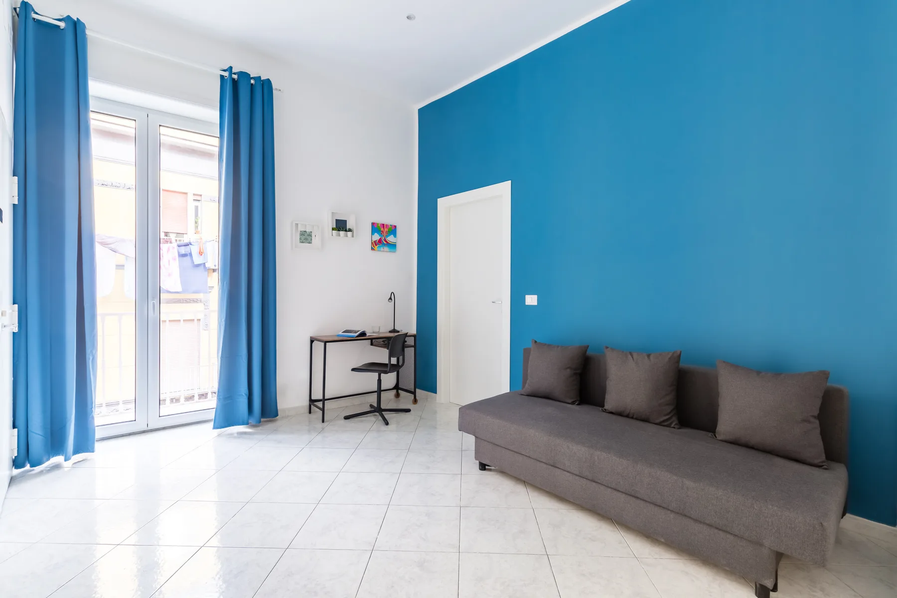 A living room with gray seating against a bright blue wall.