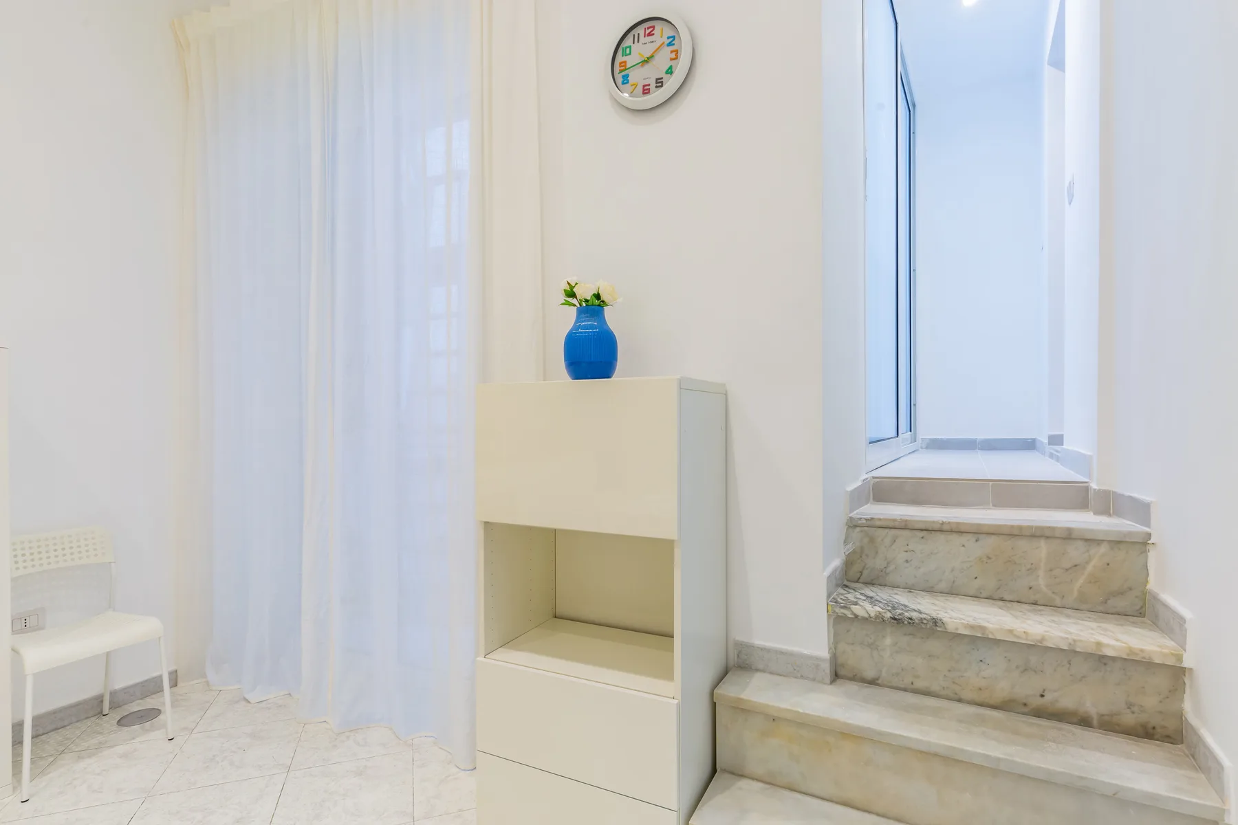 A bright interior hallway with a short staircase and a small cabinet.