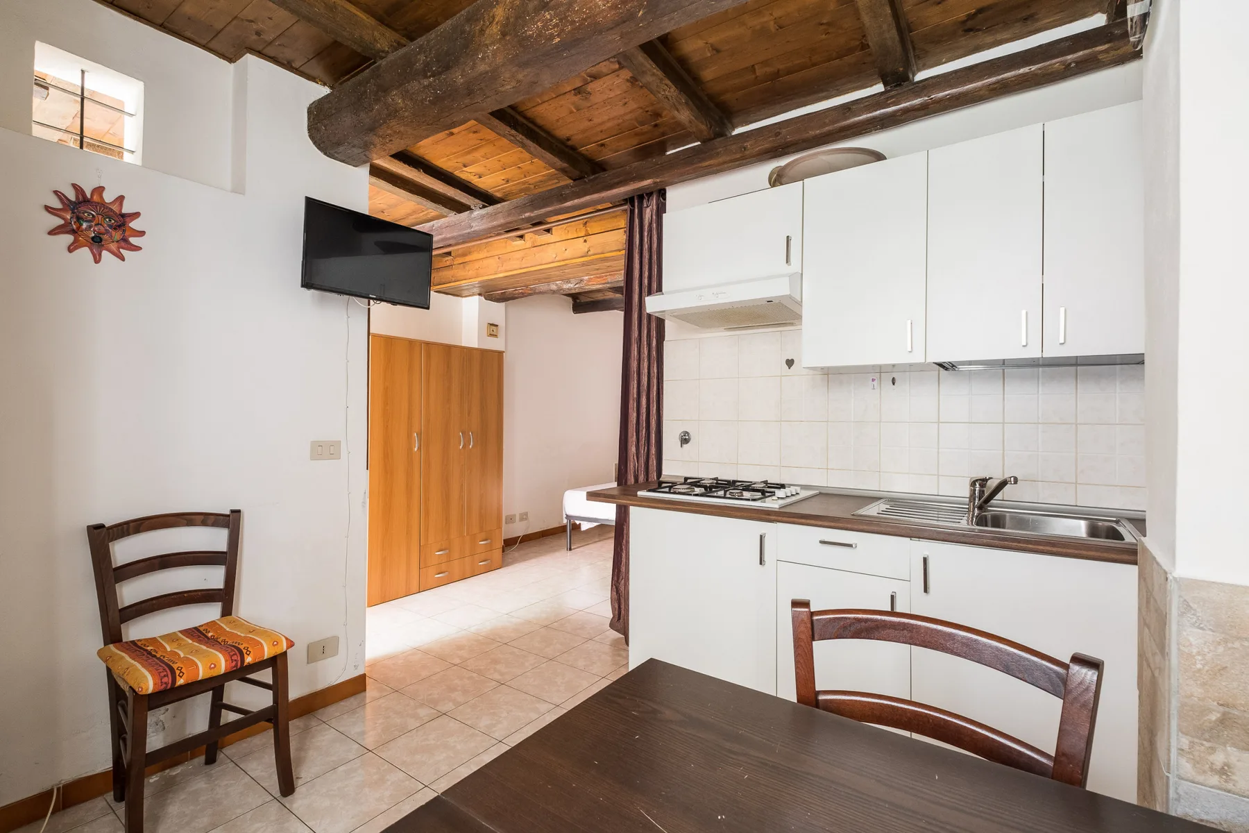 A kitchen and dining area with white cabinets and a wooden table.