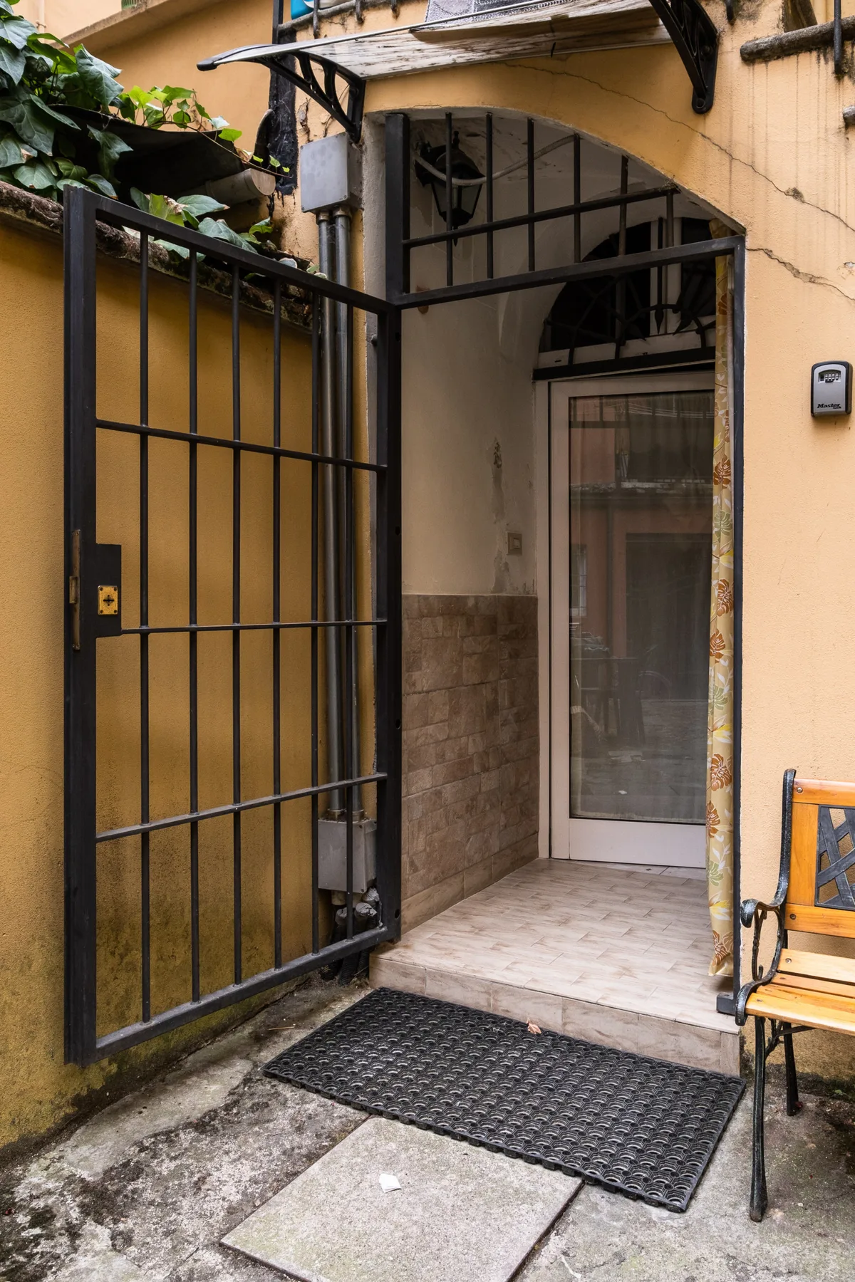 A gated entrance opens onto a small tiled entryway with a glass door.